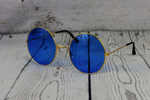 Eine modische Fassung in metallischem goldgelb mit schwarzen Bügelenden, die zwei blaue Brillengläser hält.